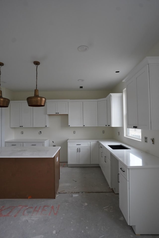 kitchen featuring hanging light fixtures, a center island, sink, and white cabinets