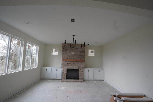 unfurnished living room with an inviting chandelier and a fireplace