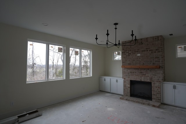 unfurnished living room featuring a brick fireplace and a notable chandelier