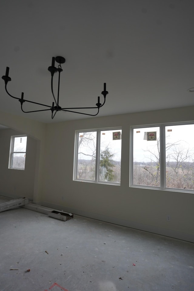 empty room featuring concrete flooring and a chandelier