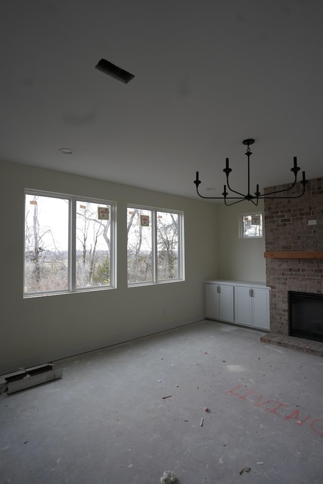 unfurnished living room with an inviting chandelier and a brick fireplace