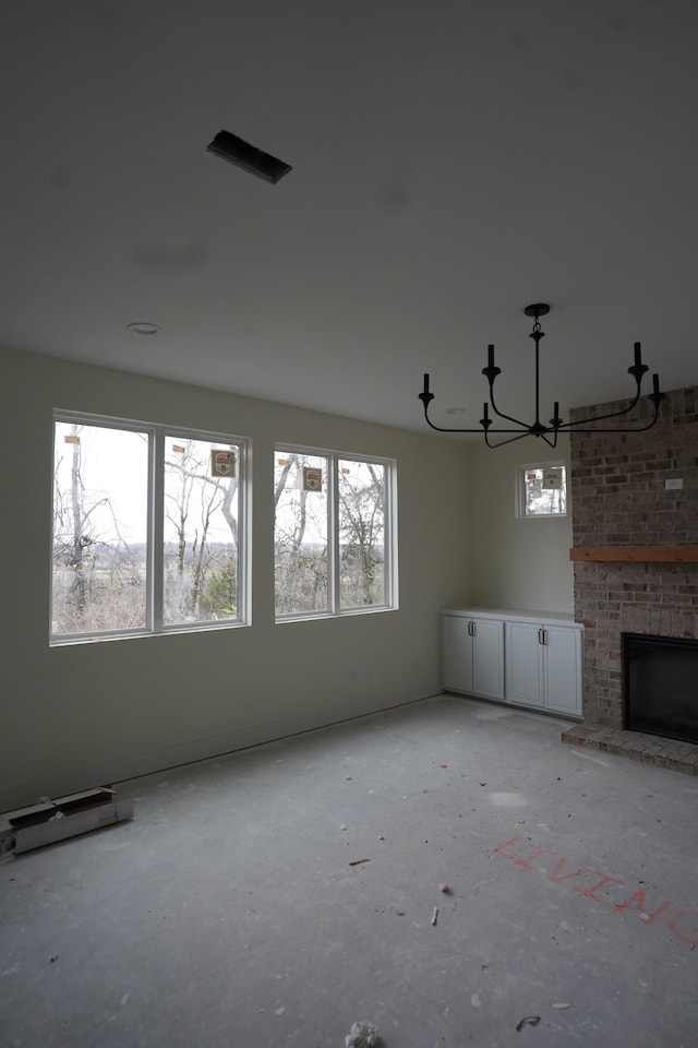 unfurnished living room with a brick fireplace and a notable chandelier