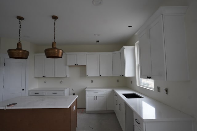 kitchen with white cabinetry, sink, pendant lighting, and a center island