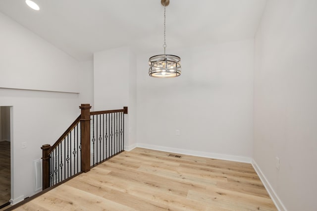 stairway with a chandelier, lofted ceiling, and wood-type flooring