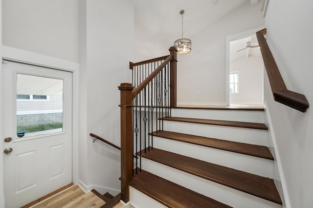 stairs featuring a chandelier, hardwood / wood-style floors, and lofted ceiling