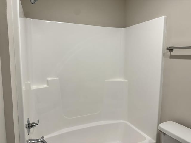 bathroom with bathing tub / shower combination and toilet