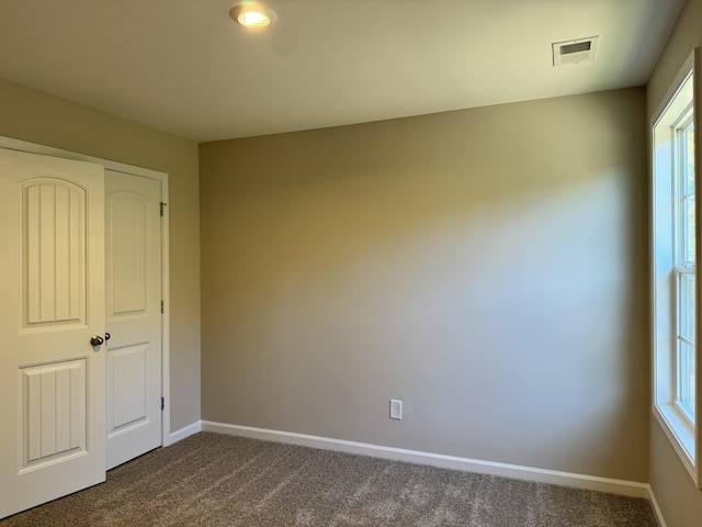 unfurnished bedroom with dark colored carpet and a closet