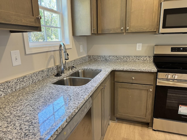 kitchen with light hardwood / wood-style floors, sink, light stone countertops, and stainless steel appliances