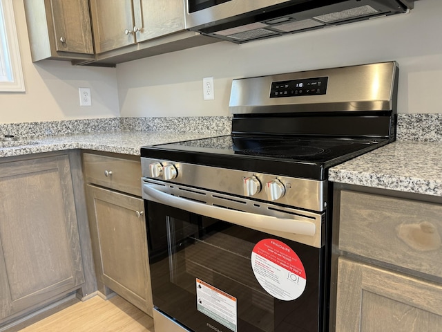 kitchen featuring light stone countertops and stainless steel electric stove