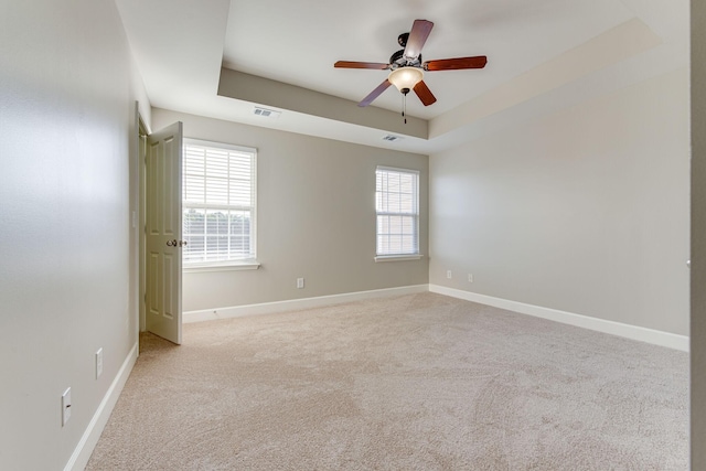 spare room with ceiling fan, a raised ceiling, and a wealth of natural light