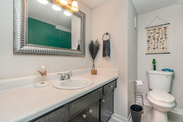 bathroom with vanity, toilet, and a textured ceiling