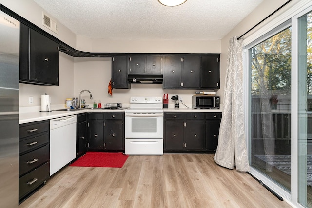 kitchen featuring a textured ceiling, light hardwood / wood-style flooring, white appliances, and sink