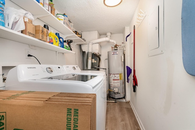 laundry area with gas water heater, washing machine and dryer, electric panel, a textured ceiling, and light wood-type flooring