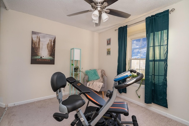 exercise room with ceiling fan, light colored carpet, and a textured ceiling