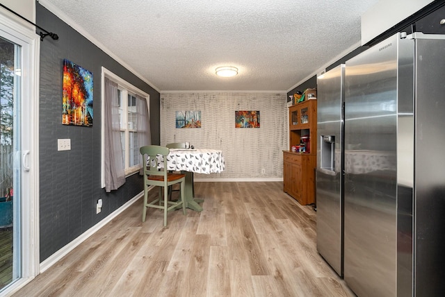 kitchen featuring stainless steel fridge, crown molding, a textured ceiling, and light wood-type flooring