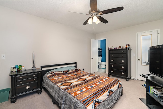 bedroom featuring ensuite bath, ceiling fan, light carpet, and a textured ceiling