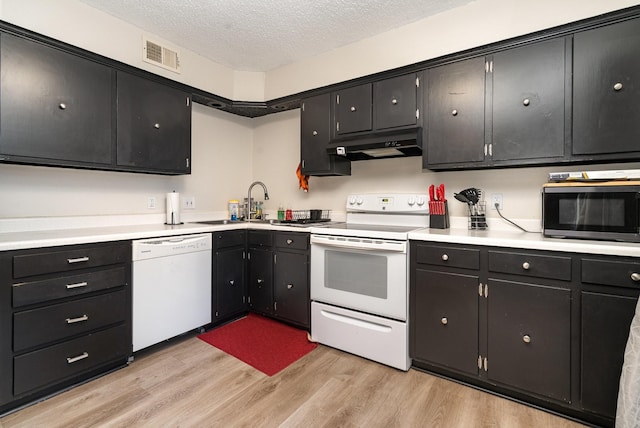 kitchen with sink, white appliances, a textured ceiling, and light hardwood / wood-style flooring