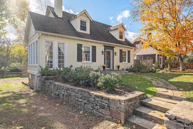 cape cod house featuring a front yard