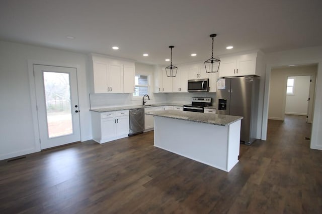 kitchen with sink, a center island, decorative light fixtures, white cabinets, and appliances with stainless steel finishes