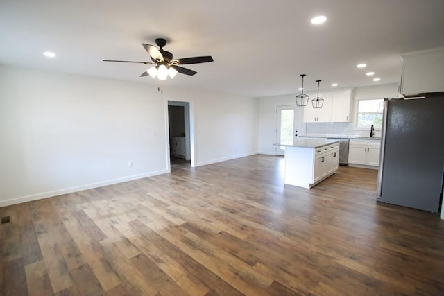 kitchen featuring white cabinetry, a center island, sink, decorative light fixtures, and appliances with stainless steel finishes