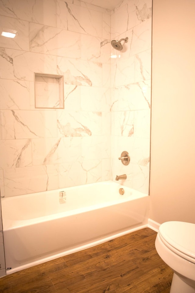 bathroom with tiled shower / bath, wood-type flooring, and toilet