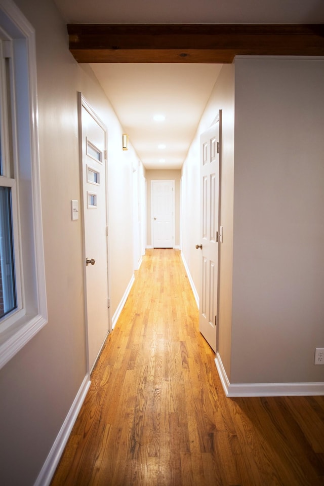 corridor with beamed ceiling and light hardwood / wood-style floors