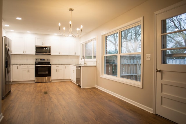 kitchen featuring appliances with stainless steel finishes, backsplash, sink, pendant lighting, and white cabinetry