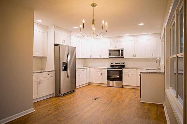 kitchen featuring white cabinets, pendant lighting, sink, and stainless steel appliances