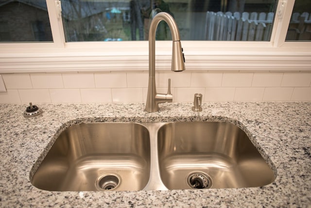 interior details with backsplash, light stone counters, and sink