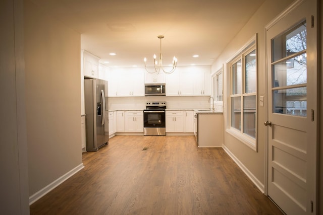 kitchen featuring white cabinets, sink, appliances with stainless steel finishes, tasteful backsplash, and decorative light fixtures