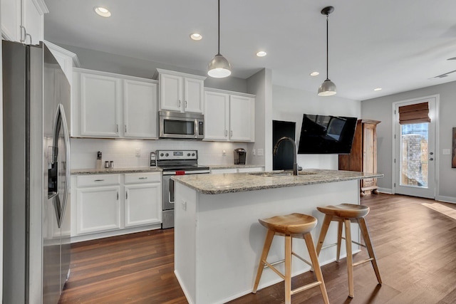 kitchen featuring decorative light fixtures, sink, white cabinetry, and stainless steel appliances