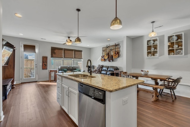 kitchen with light stone countertops, stainless steel dishwasher, a kitchen island with sink, sink, and white cabinetry