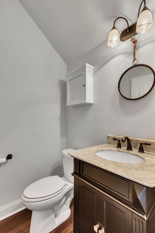 bathroom featuring vanity, toilet, wood-type flooring, and vaulted ceiling