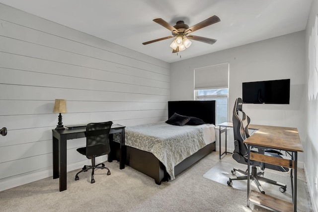 bedroom featuring ceiling fan, light carpet, and wooden walls