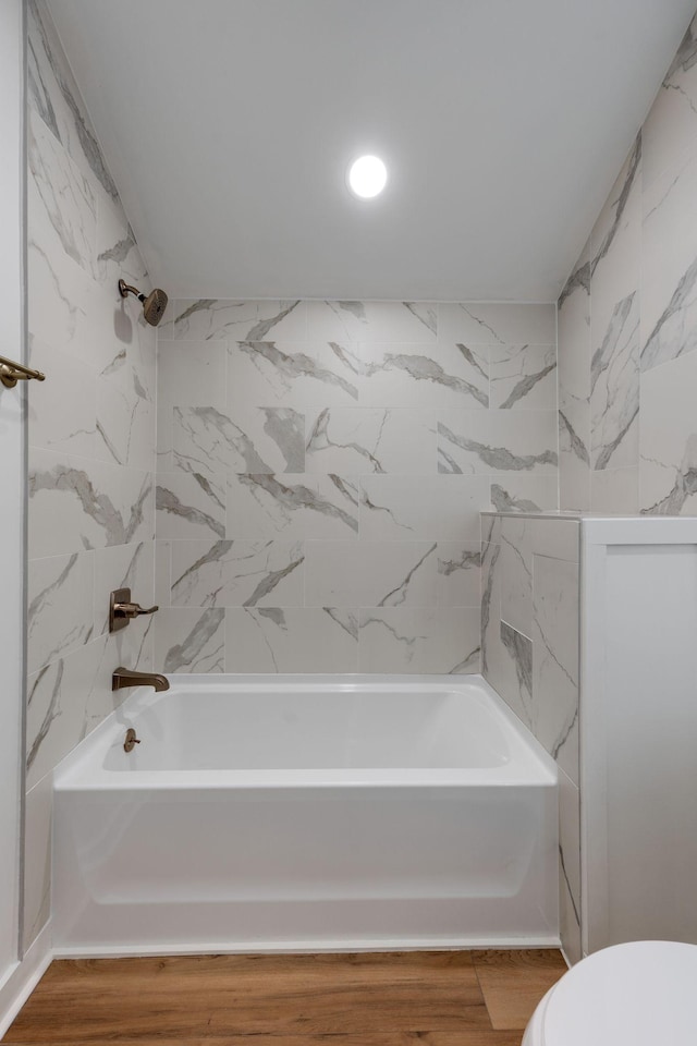 bathroom with toilet, tiled shower / bath, and hardwood / wood-style flooring