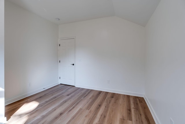 empty room with light hardwood / wood-style flooring and vaulted ceiling