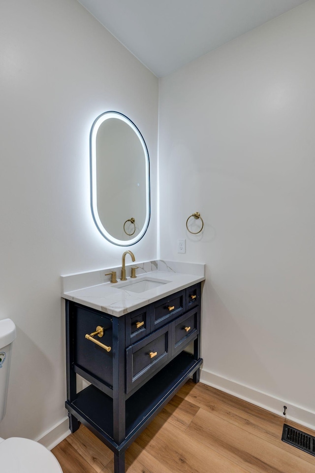 bathroom featuring toilet, vanity, and hardwood / wood-style floors