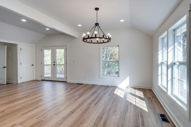 unfurnished dining area with vaulted ceiling, a chandelier, light hardwood / wood-style floors, and french doors