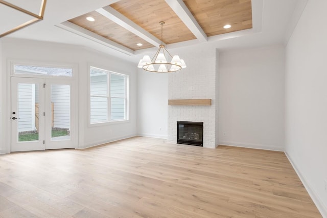 unfurnished living room with a chandelier, light hardwood / wood-style floors, wood ceiling, and a brick fireplace