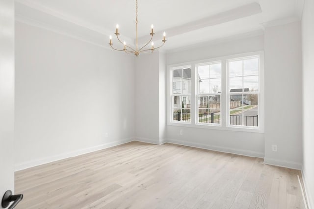 empty room featuring a notable chandelier, light wood-type flooring, and ornamental molding