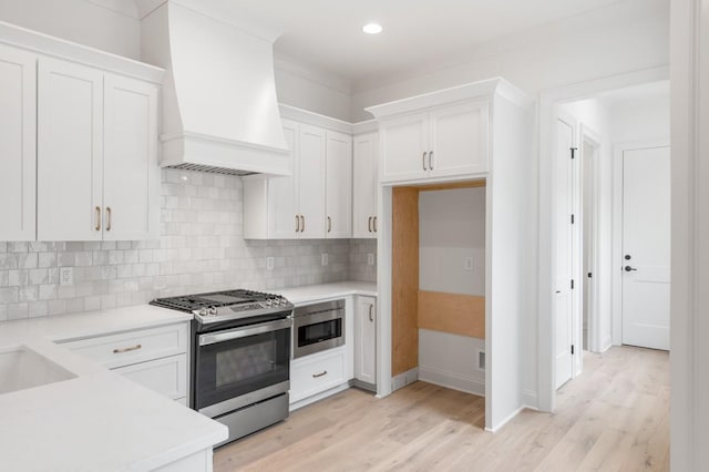 kitchen featuring white cabinets, stainless steel gas stove, premium range hood, and built in microwave