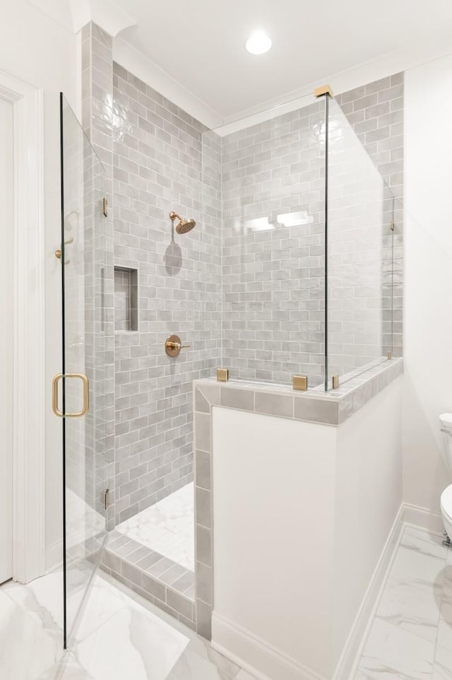 bathroom with toilet, a shower with shower door, and ornamental molding