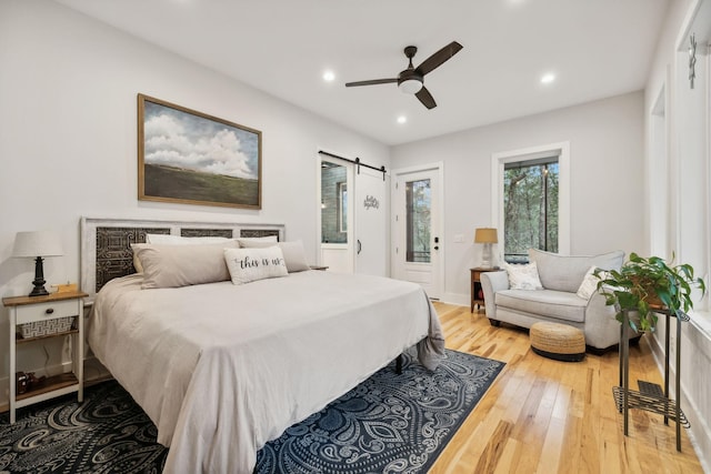 bedroom featuring hardwood / wood-style floors, ceiling fan, a barn door, and access to outside