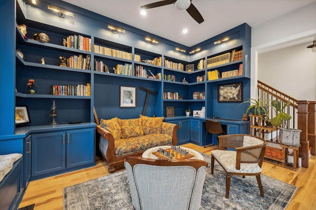 sitting room featuring built in shelves, light hardwood / wood-style floors, and ceiling fan