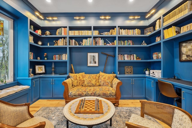 sitting room featuring built in shelves, light hardwood / wood-style floors, and built in desk