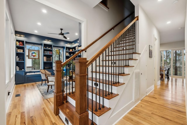 stairs with built in shelves, ceiling fan, and hardwood / wood-style flooring