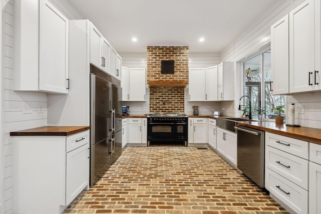 kitchen with appliances with stainless steel finishes, butcher block countertops, and white cabinetry