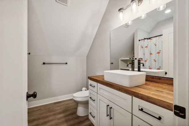 bathroom featuring hardwood / wood-style flooring, vanity, toilet, and lofted ceiling