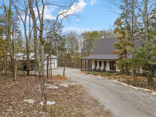 exterior space with a porch, a garage, and an outbuilding