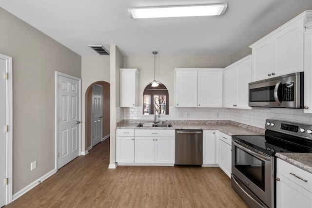 kitchen with stainless steel appliances, white cabinets, sink, and pendant lighting